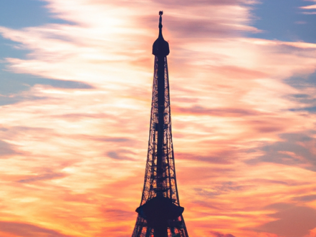 Eiffel Tower at sunset, vibrant lights illuminating the cityscape, romantic atmosphere, iconic Parisian landmark