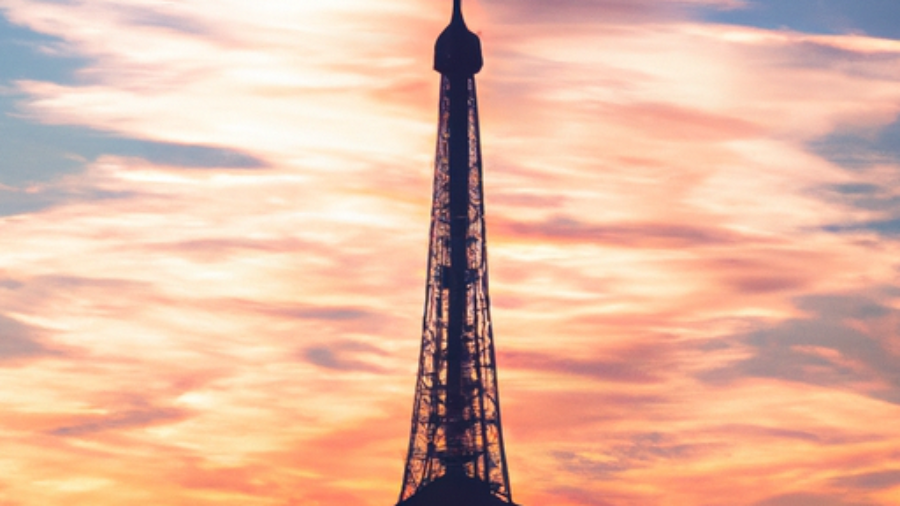 Eiffel Tower at sunset, vibrant lights illuminating the cityscape, romantic atmosphere, iconic Parisian landmark